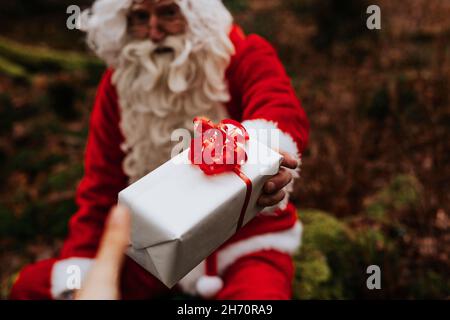 Homme portant le costume de Santa tenant présent Banque D'Images