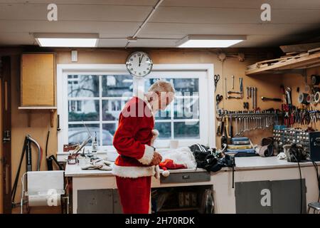 Homme senior mettant le costume de Père Noël Banque D'Images