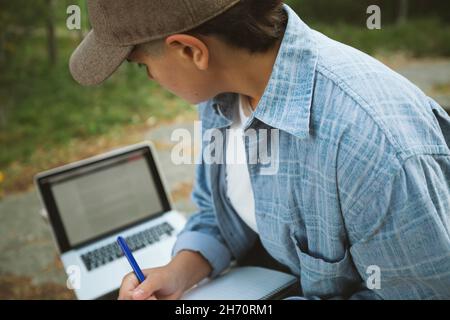 Jeune femme avec bloc-notes et ordinateur portable assis sur un banc Banque D'Images
