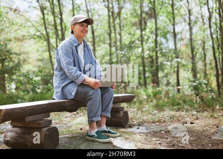 Jeune femme avec un ordinateur portable assis sur un banc Banque D'Images
