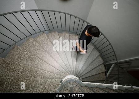 Jeune femme marchant dans un escalier en colimaçon Banque D'Images