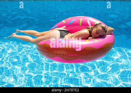 Femme dormant sur un floatie dans la piscine Banque D'Images