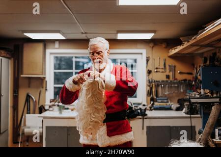 Homme senior mettant le costume de Père Noël Banque D'Images