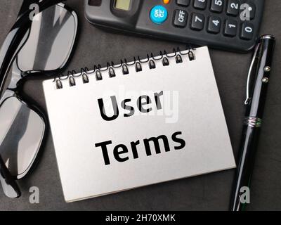 Bloc-notes, lunettes, calculatrice et stylo écrits avec des termes d'utilisation sur fond noir. Banque D'Images