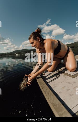 Femme en bateau libérant du poisson dans l'eau Banque D'Images