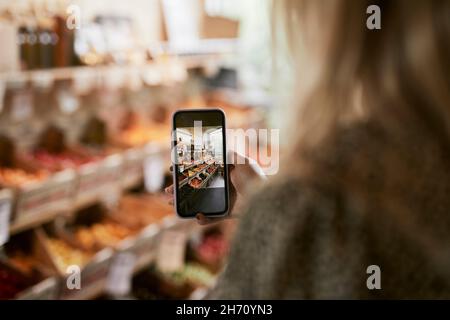 Femme prenant des photos en magasin avec des aliments biologiques Banque D'Images