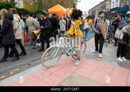 Femme à vélo prendre des photos avec téléphone mobile Columbia Road Flower Market personnes achetant des usines dans la rue en novembre 2021 East London UK KATHY DEWITT Banque D'Images