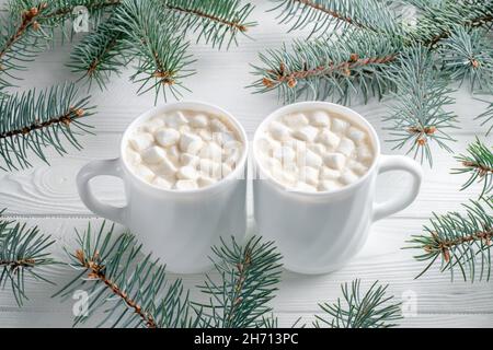 Deux tasses blanches de café avec guimauve et arbre de Noël sur table blanche en bois.Décorations du nouvel an, branches d'épinette.Saison d'hiver, composition Banque D'Images