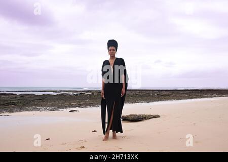 Femme debout le long de la mer avec des rochers en arrière-plan Banque D'Images