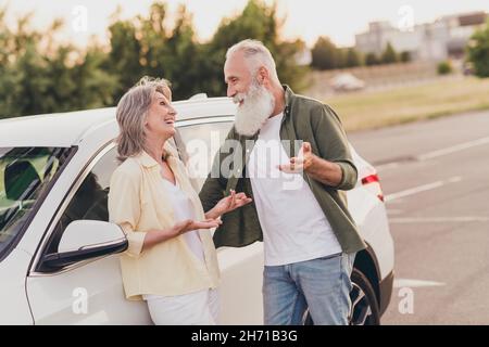 Photo de drôle belle retraite couple porter des vêtements décontractés conduite voiture parlant sourire à l'extérieur de la rue urbaine Banque D'Images