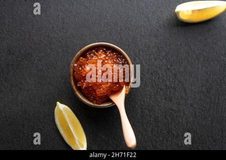 caviar rouge frais avec une cuillère en bois sur fond sombre, dans un bol en céramique. copyspace Banque D'Images