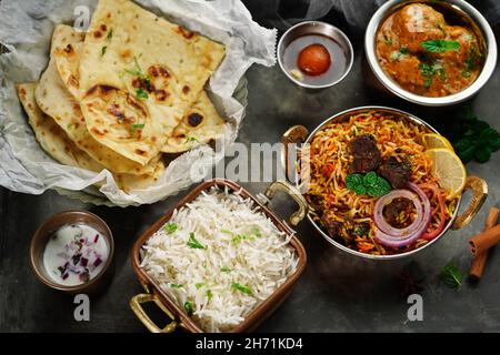 Repas indien thali - Mutton biryani, raita, kafta malai, riz basmati, naan de beurre et jamun gulab servi sur un plateau Banque D'Images