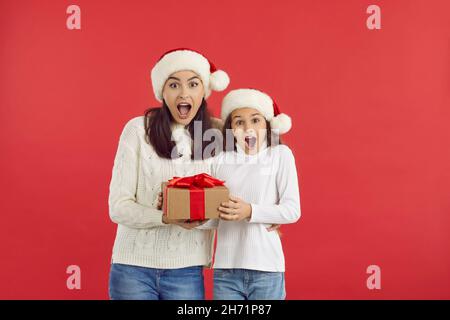 Bonne mère et enfant tenant un cadeau de Noël avec des expressions du visage surpris Banque D'Images