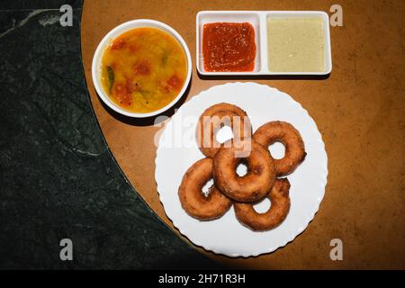 Délicieux medu wada frits du sud de l'Inde maison servi avec sambhar maison, chutney de noix de coco et chutney d'allam ou chutney rouge de gingembre.Terrain de base de Banque D'Images