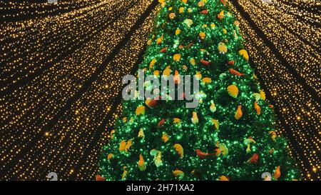 Magnifique arbre de Noël entouré de nombreuses guirlandes et décoré avec différentes boules colorées et des jouets.Arrière-plan noir.Photo de la nouvelle année. Banque D'Images