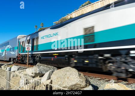 San Clemente, CA, États-Unis – 13 novembre 2021 : le train de banlieue Métrolink en mouvement flou passe un panneau de non intrusion à San Clemente, Californie. Banque D'Images