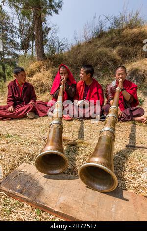 De jeunes moines bouddhistes pratiquant la corne tibétaine de dungchen à l'école monastique Dechen Phodrang à Thimphu, au Bhoutan. Banque D'Images