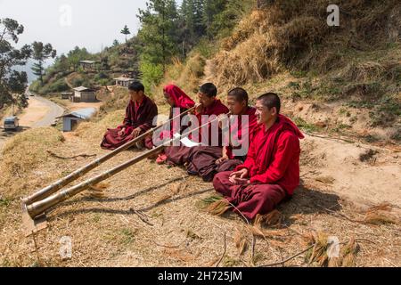 De jeunes moines bouddhistes pratiquant la corne tibétaine de dungchen à l'école monastique Dechen Phodrang à Thimphu, au Bhoutan. Banque D'Images