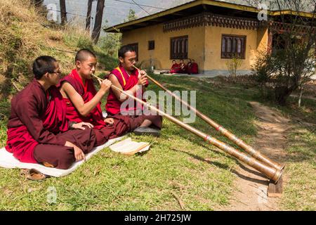 De jeunes moines bouddhistes pratiquant la corne tibétaine de dungchen à l'école monastique Dechen Phodrang à Thimphu, au Bhoutan. Banque D'Images