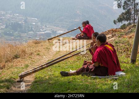 De jeunes moines bouddhistes pratiquant la corne tibétaine de dungchen à l'école monastique Dechen Phodrang à Thimphu, au Bhoutan. Banque D'Images