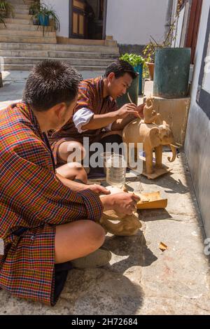 Deux jeunes hommes sculptant dans le bois à l'École nationale des arts de Thirsteen à Thimphu, au Bhoutan. Banque D'Images