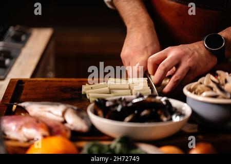 Faire cuire le céleri sur la planche à découper entourée d'une variété d'ingrédients.Mollusques frais crevettes en coquille de poisson.Cuisiner des fruits de mer. Banque D'Images