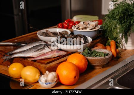 La dorade et les coquillages sur la table à côté des légumes et des fruits.Ingrédients pour préparer une délicieuse soupe. Banque D'Images