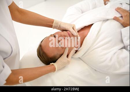Portrait en grand angle d'un beau homme âgé bénéficiant d'un massage du visage au centre de spa de luxe, espace de copie pour la publicité. Banque D'Images