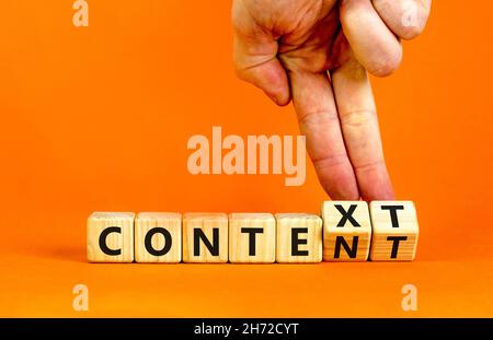 Symbole de contenu et de contexte.Homme d'affaires tourne des cubes en bois et change le mot contexte en contenu.Belle table orange, fond orange.Affaires Banque D'Images