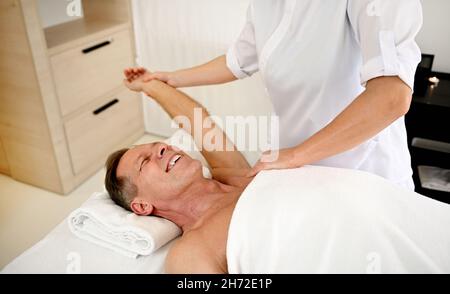 Femme massothérapeute court effectuant un massage corporel à un homme d'âge moyen charmant, client d'un centre de spa de luxe.Soins du corps pour hommes, beauté t Banque D'Images