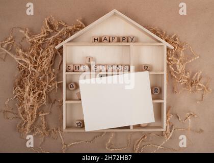 Concept de Noël écologique minimal.Maison en bois et carte vierge pour votre texte.Décoration de noël bio durable à faire soi-même. Banque D'Images