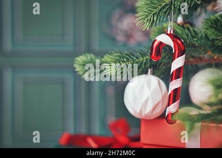 Décoration de noël en forme de canne à sucre sur l'arbre avec cadeaux sur le côté d'un fond vert Banque D'Images