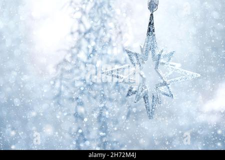 Décoration de Noël avec effet neige tombant.Étoile argentée bleu clair Banque D'Images