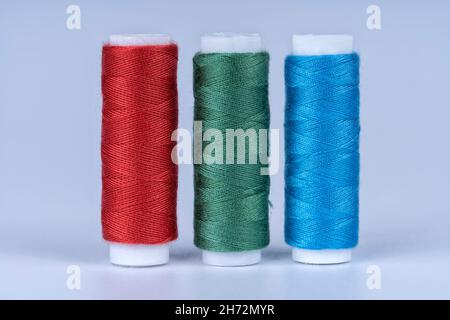 Trois bobines de fil à coudre de couleurs rouge vert et bleu isolées sur fond blanc Banque D'Images