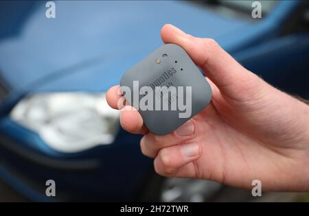 Un jeune conducteur sur le point d'installer une boîte noire télématique d'assurance automobile au Royaume-Uni dans sa nouvelle voiture. Banque D'Images