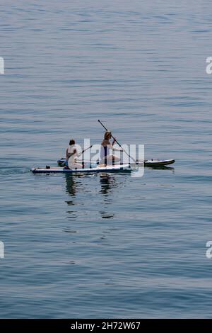 Deux femelles paddleboard sur un très calme, chaud jour de juillet, près de Charlestown, sud de Cornwall, Royaume-Uni. Banque D'Images