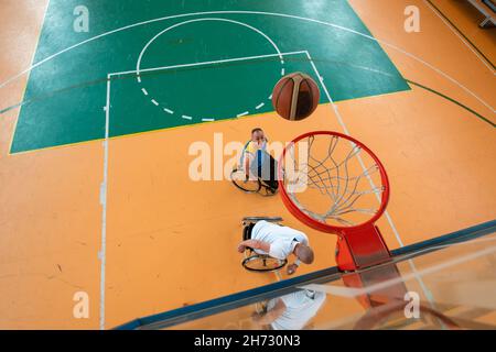 Les vétérans handicapés de guerre ou de travail ont mélangé des équipes de basket-ball de race et d'âge en fauteuil roulant jouant un match d'entraînement dans une salle de sport.Personnes handicapées Banque D'Images