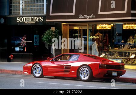 Homme assis dans une voiture de sport rouge Ferrari garée sur Rodeo Drive à Beverly Hills, CA Banque D'Images