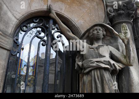 Une statue à bras levé se dresse à l'entrée en verre d'un mausolée du cimetière historique de Passy (Cimetière de Passy) à Paris. Banque D'Images