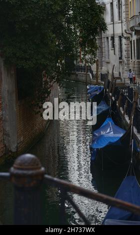 un canal étroit avec des gondoles amarrées et couvertes Banque D'Images