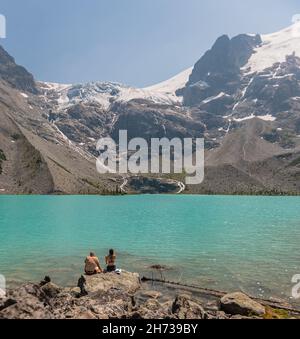 Un jeune couple est assis sur un grand rocher et bénéficie d'une vue majestueuse sur un lac de montagne.Vue sur la piste du lac Upper Joffre.Lac Joffres dans le parc provincial dans Banque D'Images