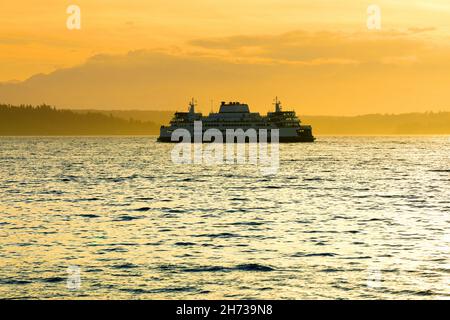 Grand ferry naviguant sur l'eau au coucher du soleil Banque D'Images