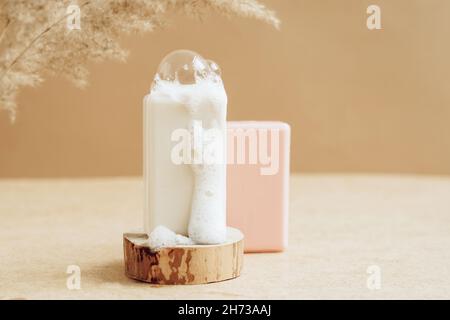 Un morceau de savon naturel bio fait main avec de grandes bulles de mousse sur un podium moderne abstrait. Banque D'Images