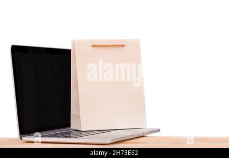 Ordinateur portable et sac à provisions sur une surface en bois.Isolation sur fond blanc Banque D'Images