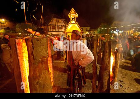 FRANCE, HAUT-RHIN (68), RIBEAUVILLA©, PLACE DE LA RÉPUBLIQUE, MARCHÉ DE NOËL MÉDIÉVAL,BROCHETTE DE BACON GRILLÉ SUR LE BRAZIER (BOIS SUÉDOIS) Banque D'Images