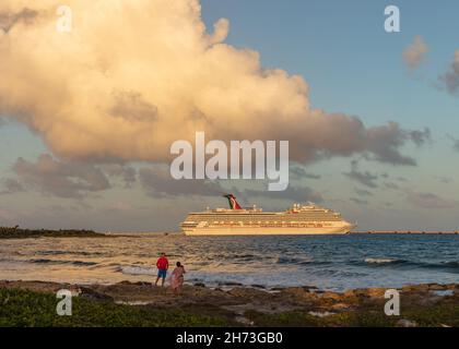 Cozumel, Mexique - 11 février 2020 : Carnaval Freedom amarré dans le port de Costa Maya au coucher du soleil orange.Deux touristes, la ligne de rivage, des vagues éclaboussant dans le for Banque D'Images