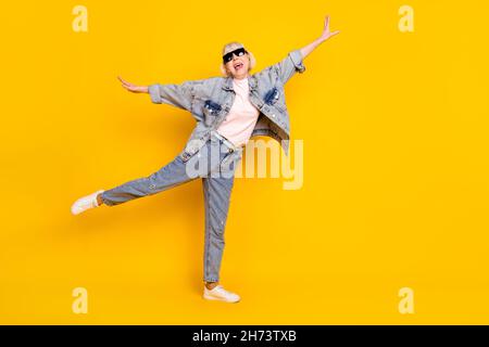 Photo de la taille du corps sur toute la longueur d'une femme âgée portant un ensemble de denim de lunettes de soleil sans attention isolé couleur jaune vif arrière-plan Banque D'Images