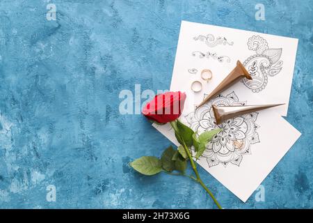 Le henné peint et ornement exemples avec rose rouge et bijoux sur fond bleu texturé Banque D'Images