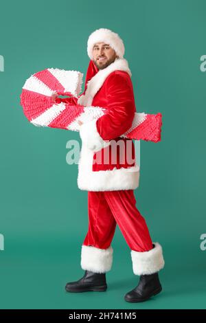 Père Noël avec pinata de canne à sucre sur fond vert Banque D'Images