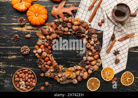 Belle couronne de glands, tasse de café, citrouilles et noisettes sur fond de bois noir Banque D'Images